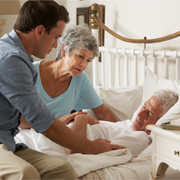 Older man in bed surrounded by family