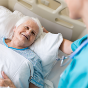 Older woman in bed, nurse visiting