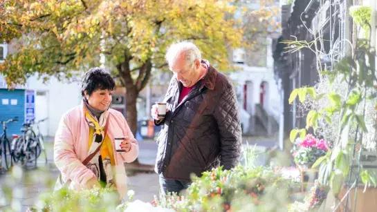 old woman and man drinking coffee outside